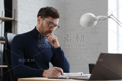 建筑师在办公室里设计蓝图。工程师检查建筑平面图，为建筑工程画草图。长着胡须的英俊男子坐在工作场所的肖