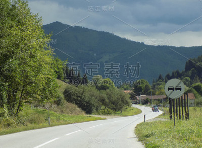 汽车行驶在带有“禁止超车结束”路标的山路上，经过住宅区
