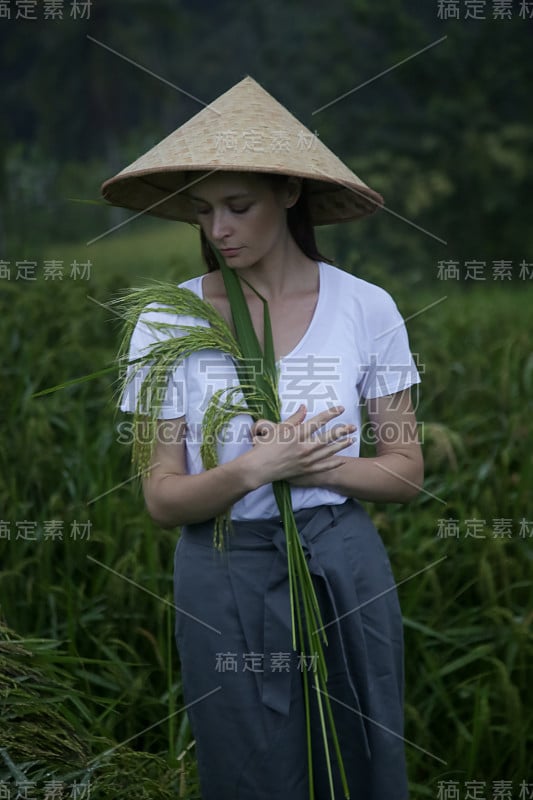 戴着传统竹帽的妇女站在稻田梯田上