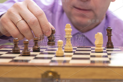 男人若有所思地看着棋子，手里拿着一枚。