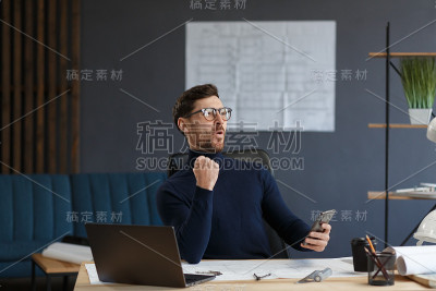 年轻人微笑着用智能手机。快乐的商人使用手机应用程序，发短信，浏览互联网，看智能手机。年轻人使用移动设