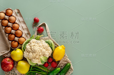 绿色背景下的零浪费购物理念。餐桌上的新鲜蔬菜和水果用环保棉袋包装。