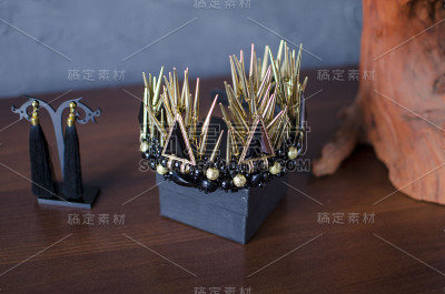 美丽的金色时尚皇冠与黑色宝石和刺。木桌上放着黑色的耳环和金色的王冠