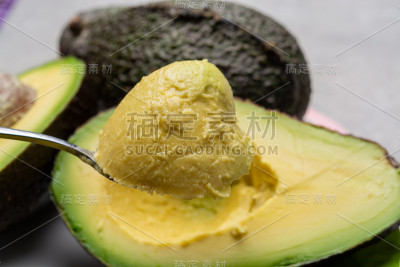 用勺子吃新鲜熟透的绿色有机牛油果