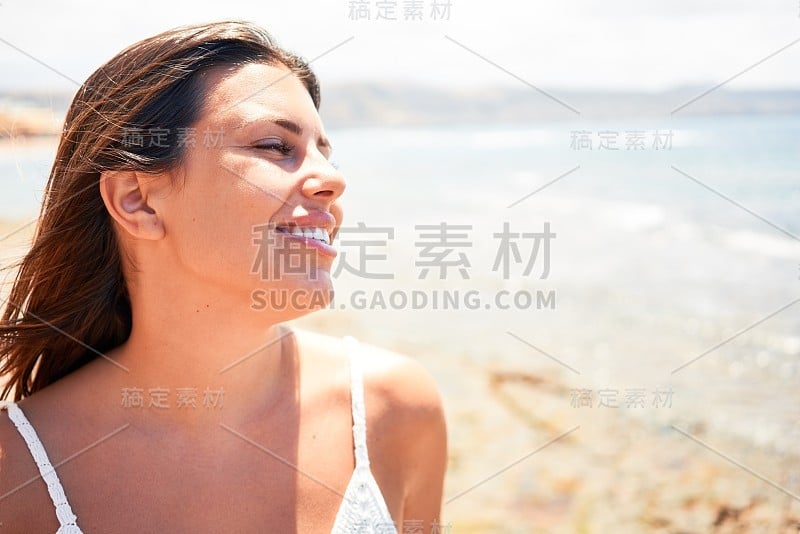 美丽的年轻女子走在海滩散步欣赏海景微笑愉快的暑假