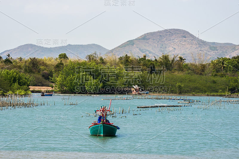 渔船停泊在群山环绕的海岸上。