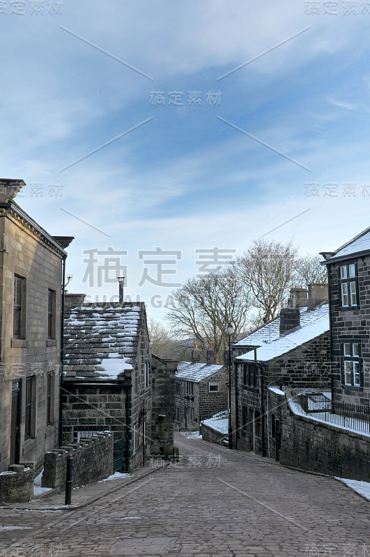 这是约克郡西部赫普顿斯托尔村的主要街道，屋顶上覆盖着积雪，冬天天空湛蓝