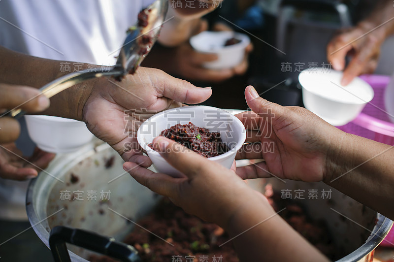 地球上乞丐问题的概念:乞丐的手接受来自人类同胞的慈善食物:难民的手得到了慈善食物的帮助，以减轻饥饿