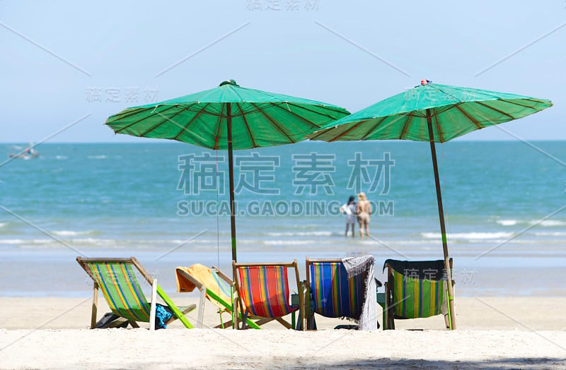 沙滩上的帆布床和雨伞背景模糊旅游和大海。