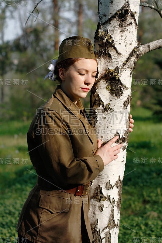 漂亮的苏联女兵穿着二战制服站在桦树旁