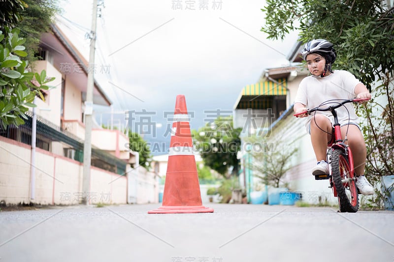 孩子在学骑自行车。通过练习骑着交通锥