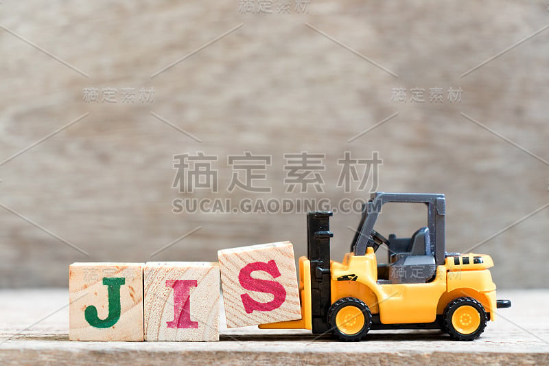 玩具叉车把字母块s字JIS (Just in order的缩写)放在木头背景上