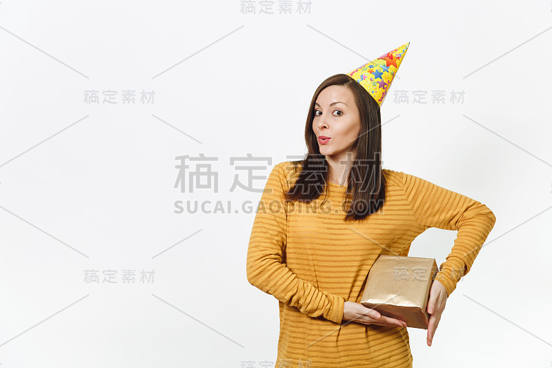 快乐的白人有趣的年轻幸福的女人在黄色的衣服，生日派对帽子拿着金色的礼盒与礼物，庆祝和享受假期的白色背