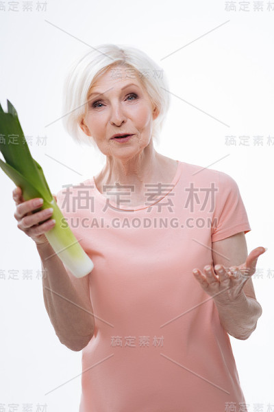 惊讶的老妇人右手拿着韭菜