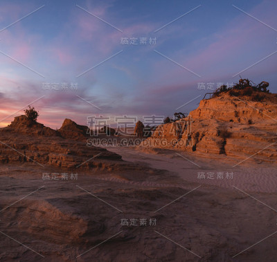 广角的沙漠景观与粘土岩石形成在柔和的彩色日落光
