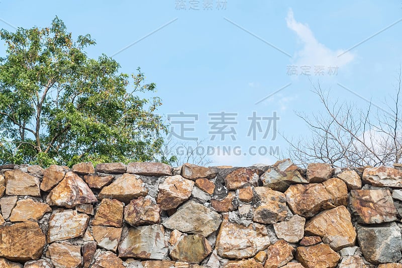 特写的石头砖栅栏与模糊的树和蓝天纹理背景