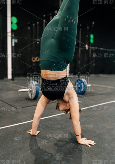 年轻女子在健身房地板上做倒立行走训练