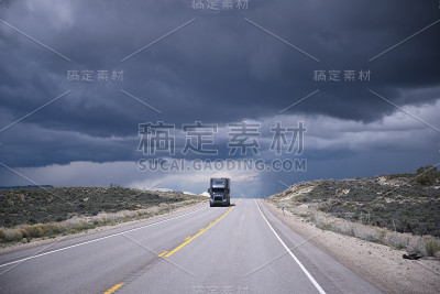 深灰色的半卡车在高速公路上和暴风雨的天空