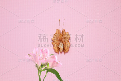 一只用剥了皮的核桃粒做成的蝴蝶坐在一束百合上。