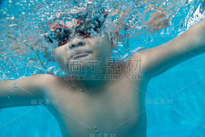 快乐的亚洲小孩在水下戴着泳镜
