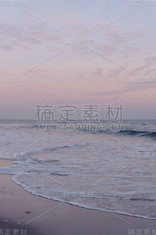 日落时，平静的海浪在海滩上翻滚