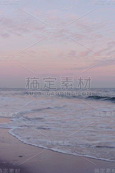 日落时，平静的海浪在海滩上翻滚