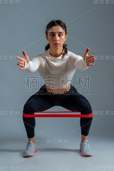 在灰色背景下做下蹲的女孩