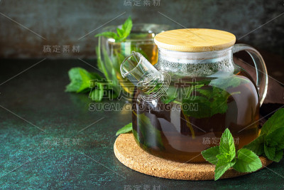 治疗花草茶。在黑色石头或混凝土背景上放上热薄荷茶。副本的空间。