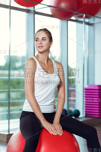 年轻的女运动员在健身房用健身球做运动