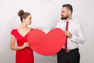 美丽的情侣互相看着，捧着红红的心，他们的爱情