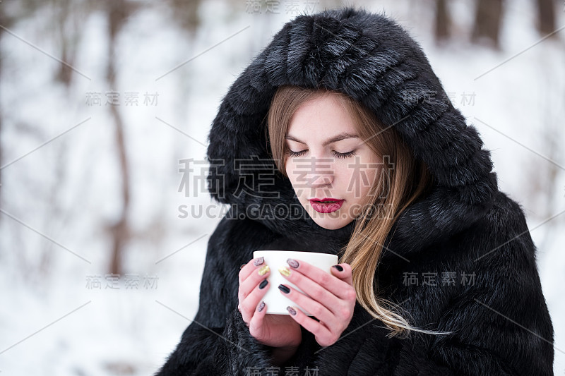 女孩用白色的杯子喝茶。