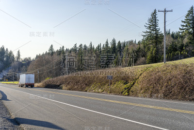 大型半挂车与散装长半挂车运输货物在笔直的道路与树木在山坡上