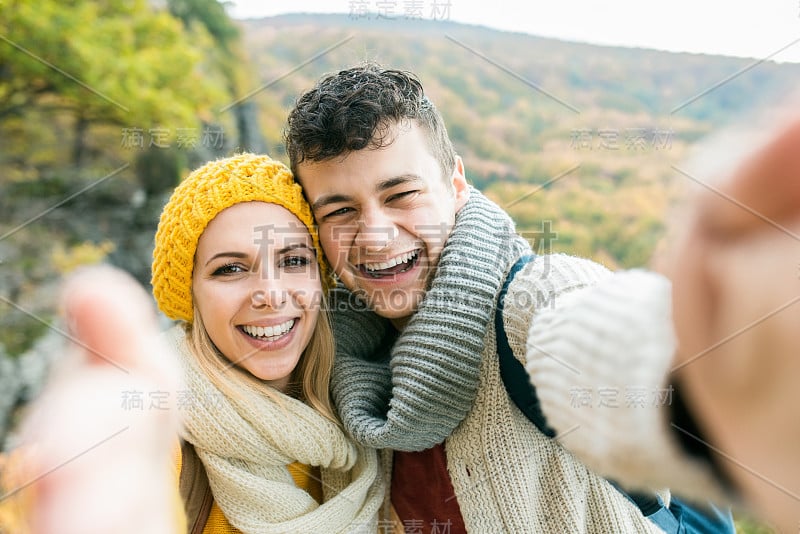 一对年轻夫妇在秋天的森林里散步自拍