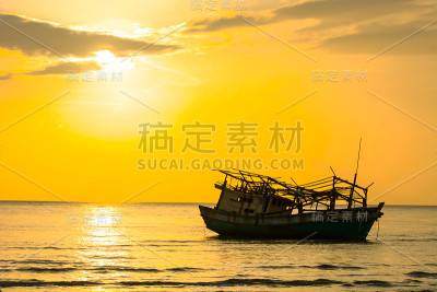 落潮时搁浅的渔船，背景是金色的天空和夕阳