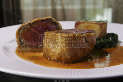 盘上惠灵顿牛肉，惠灵顿牛肉牛排配菠菜和炸土豆。关闭了。
