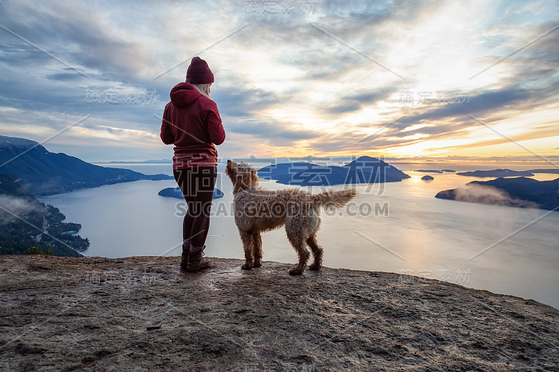 爱冒险的女孩带着狗在山顶徒步旅行