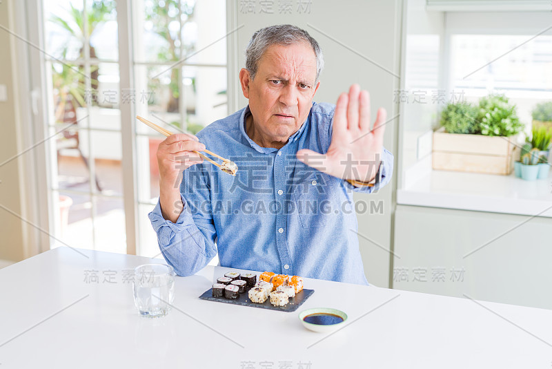 英俊的老男人在家里用筷子吃外卖寿司，张开手做停止手势，严肃自信的表情，防御手势