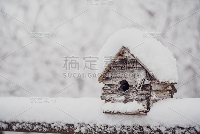 风化的木头鸟笼，栏杆上覆盖着新雪。