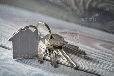 房子的钥匙与钥匙链在白色木制背景