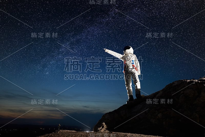 宇航员站在岩石山在夜空下繁星点点。