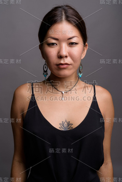 摄影室拍摄的年轻亚洲女性穿着正式的黑色连衣裙，背景是灰色