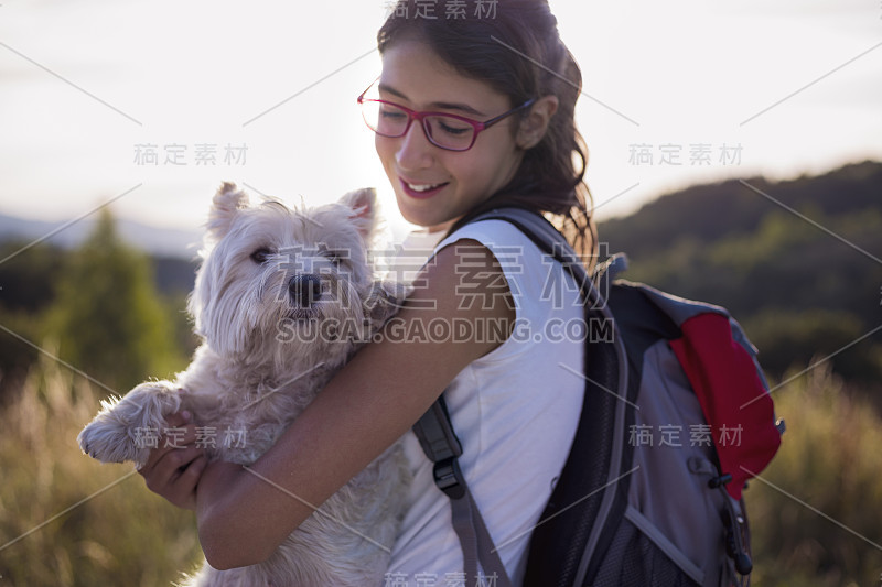 微笑的女孩背着背包和狗