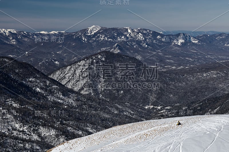 在俄罗斯阿迪加国家自然保护区白雪覆盖的山顶上，一名孤独的骑手。欢迎来到俄罗斯。