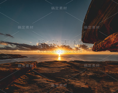 广角长曝光日出以上的海洋地平线和砂岩岩层