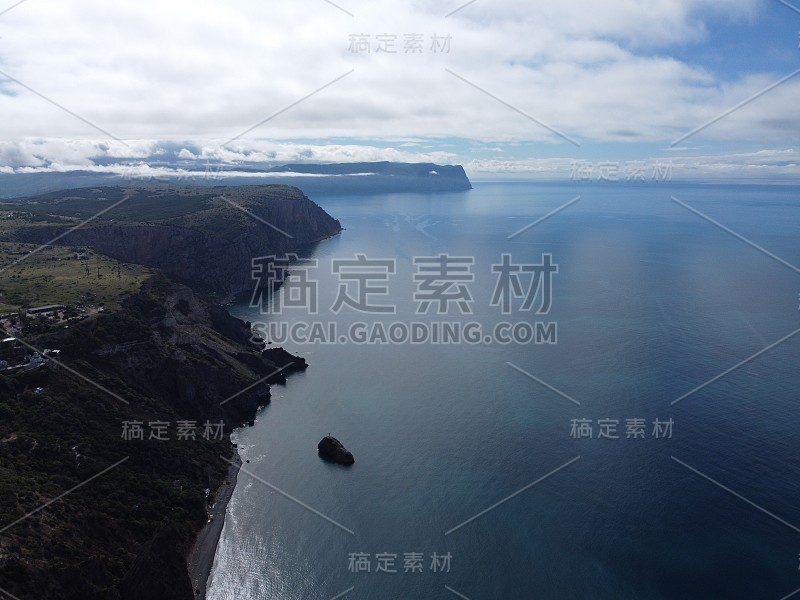 从上面鸟瞰蔚蓝的大海和火山岩石海岸。水面上的小波浪动态模糊。大自然夏季海洋海滩背景。没有人。假日，假