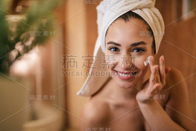 在浴室里给脸涂保湿霜的美女。