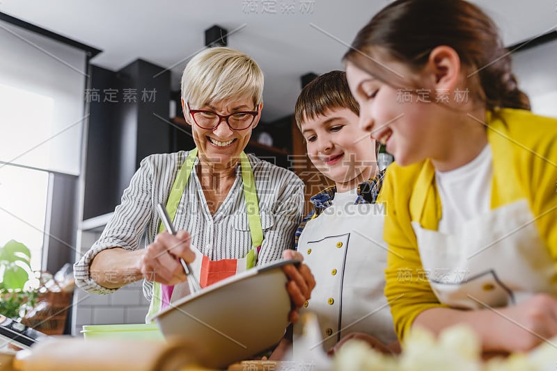 奶奶和她的孙子在厨房里一起做蛋糕。