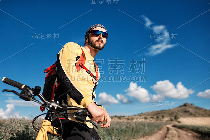 骑山地自行车的人骑在日落山谷的单轨上