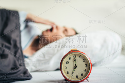 女人睡在床上，闹钟。