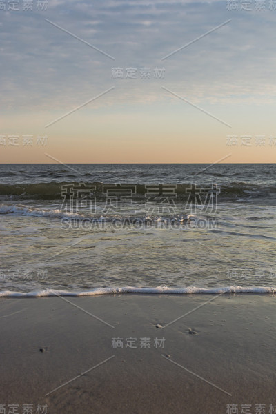 日落时，平静的海浪在海滩上翻滚